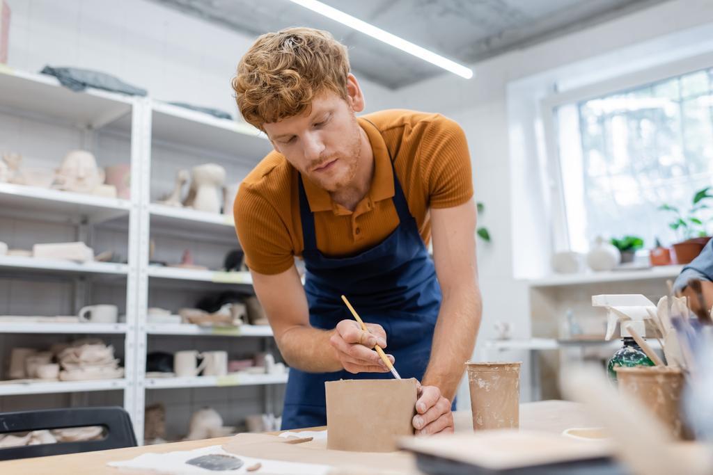 бородатий чоловік у фартусі тримає дешевше під час моделювання глини під час класу кераміки
  - Фото, зображення