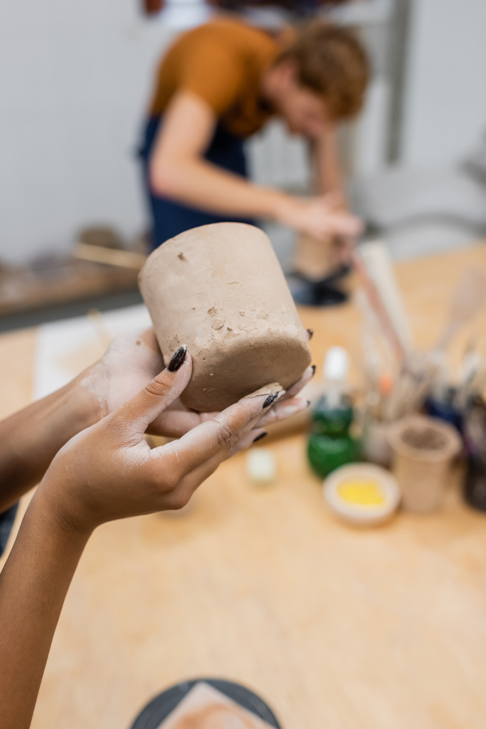vista parziale della donna afro-americana stampaggio tazza di argilla in mano - Foto, immagini