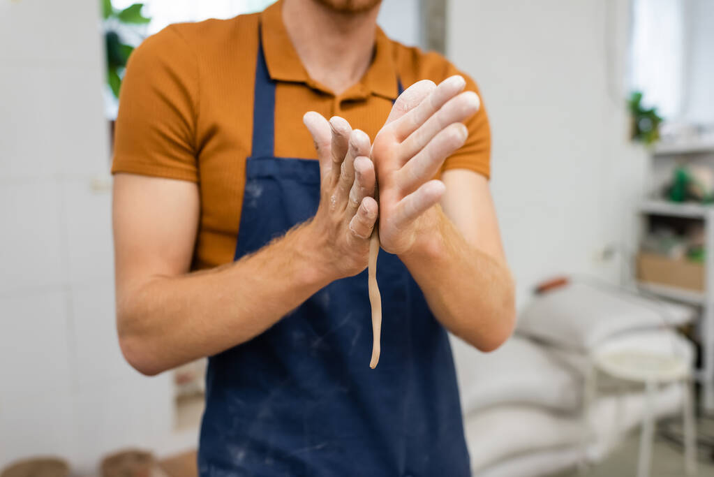 Ausgeschnittene Ansicht eines Handwerkers beim Formen von Ton im Töpferatelier  - Foto, Bild
