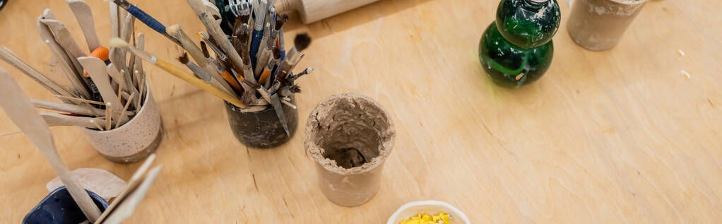 ワークショップでテーブルの上の粘土や陶器のツールのトップビュー、バナー  - 写真・画像