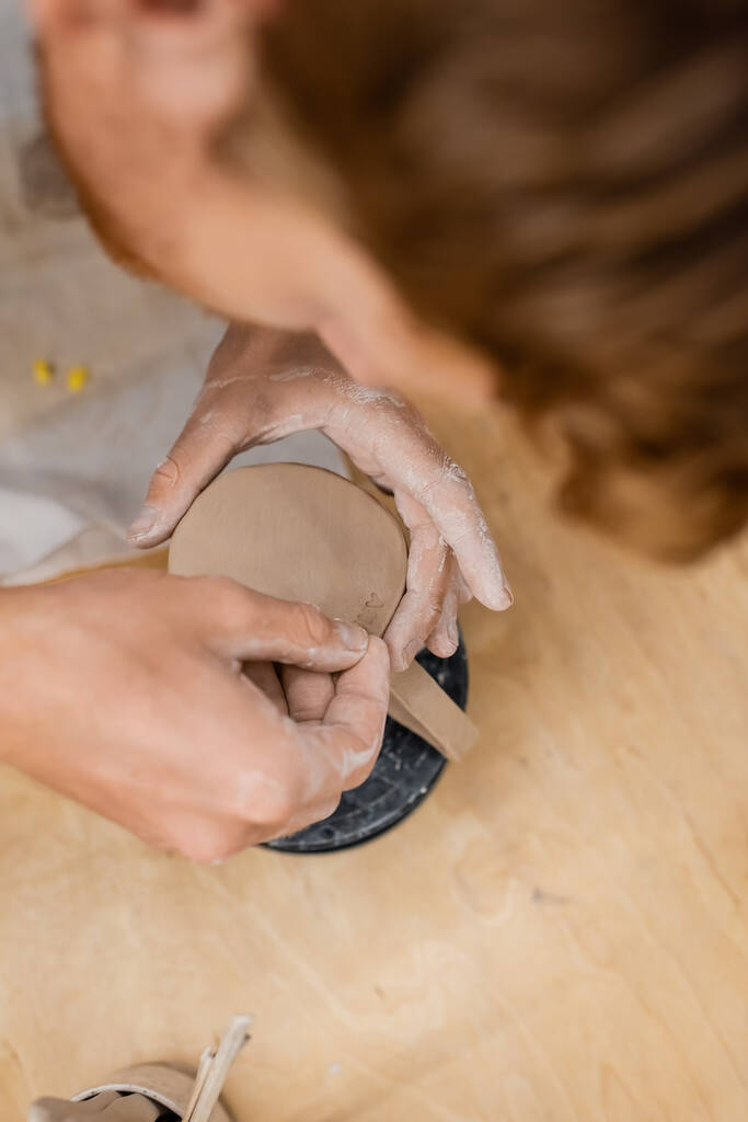 Vista aérea de artesano creando signos en taza de arcilla en taller de cerámica  - Foto, imagen