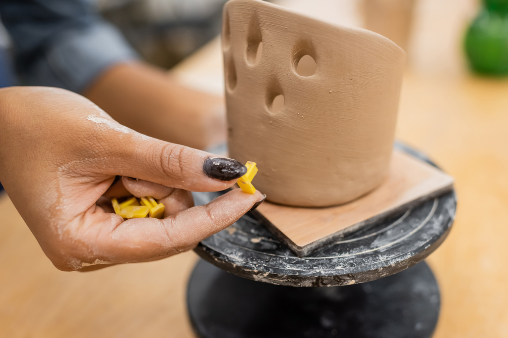 Vista ritagliata dell'artigiana afro-americana che tiene strumenti vicino alla scultura in argilla in officina  - Foto, immagini
