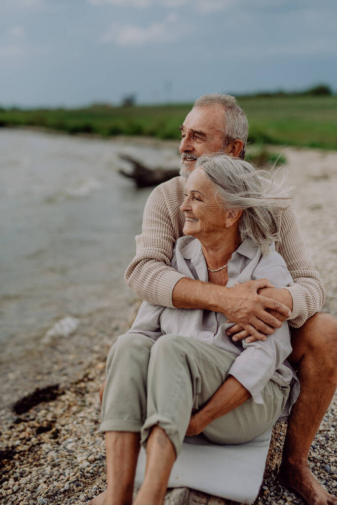 Seniorenpaar sitzt und hat romantischen Moment am Herbstmeer. - Foto, Bild