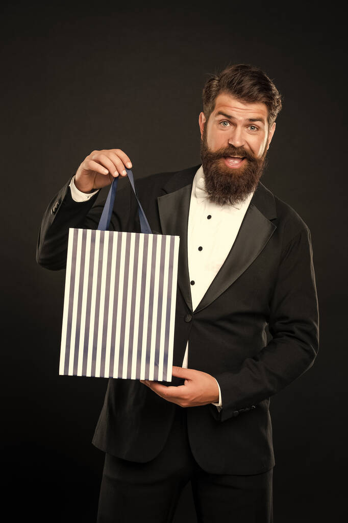homem alegre em smoking arco gravata formalwear no fundo preto com saco de compras. Aniversário. espaço de cópia. - Foto, Imagem