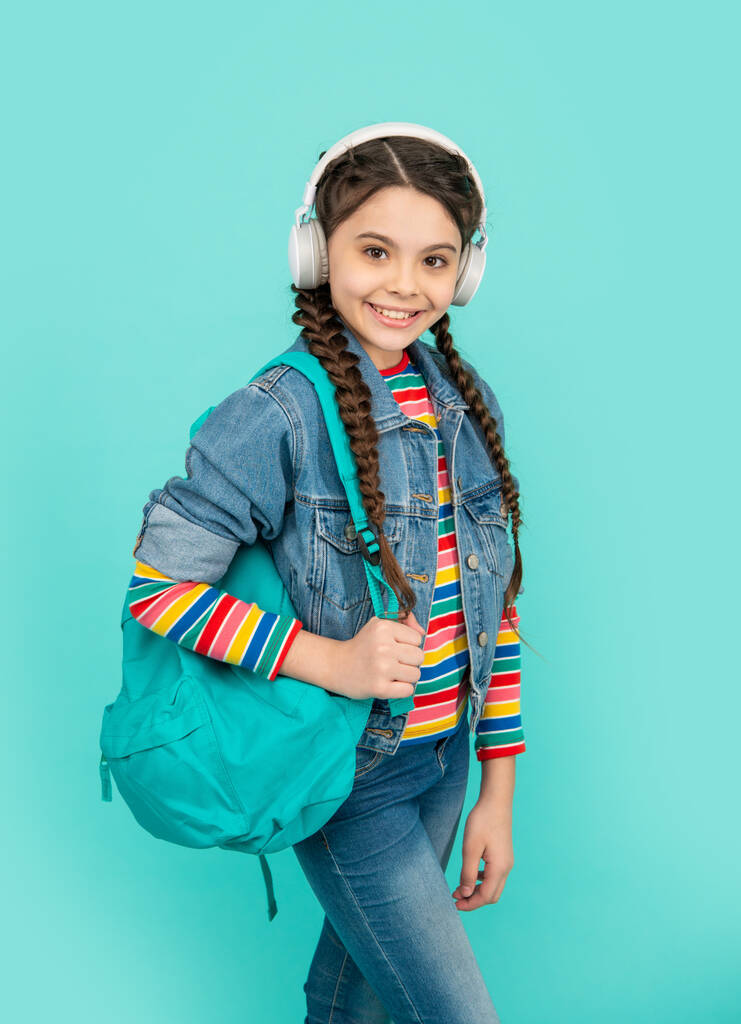 Happy girl teenager listening to music in headphones blue background, education. Informal education. School education. - Photo, Image