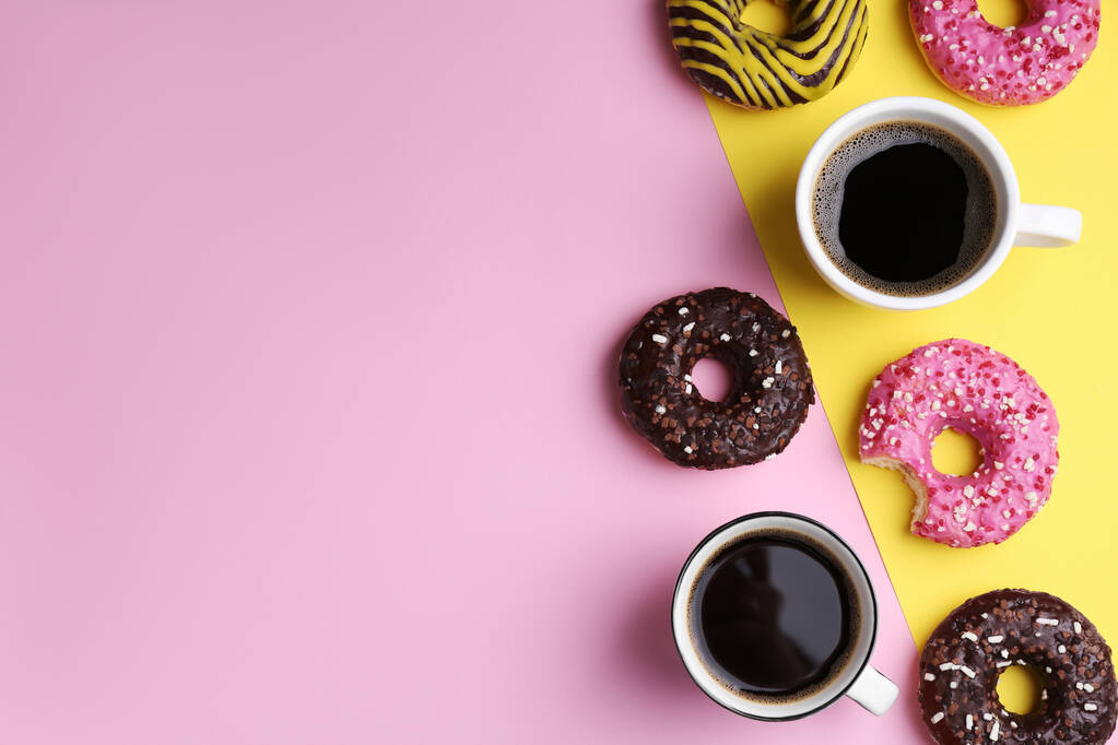 Donuts saborosos e xícaras de café no fundo de cor, flat lay. Espaço para texto - Foto, Imagem