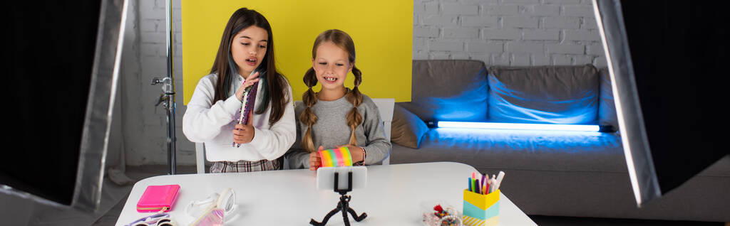κορίτσια με σημειωματάριο και σπιράλ παιχνίδι εγγραφής βίντεο blog στο smartphone στο σπίτι, πανό - Φωτογραφία, εικόνα