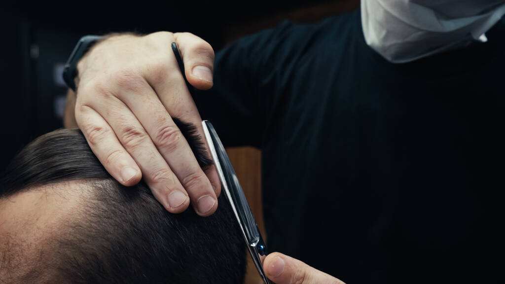 Oříznutý pohled na kadeřníka v lékařské masce stříhání vlasů zákazníka v holičství  - Fotografie, Obrázek