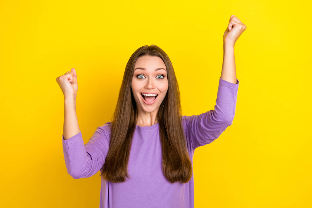 Photo of crazy positive charming woman wear stylish purple shirt fists up crazy emotion celebrate victory her favorite team isolated on yellow color background. - Photo, Image
