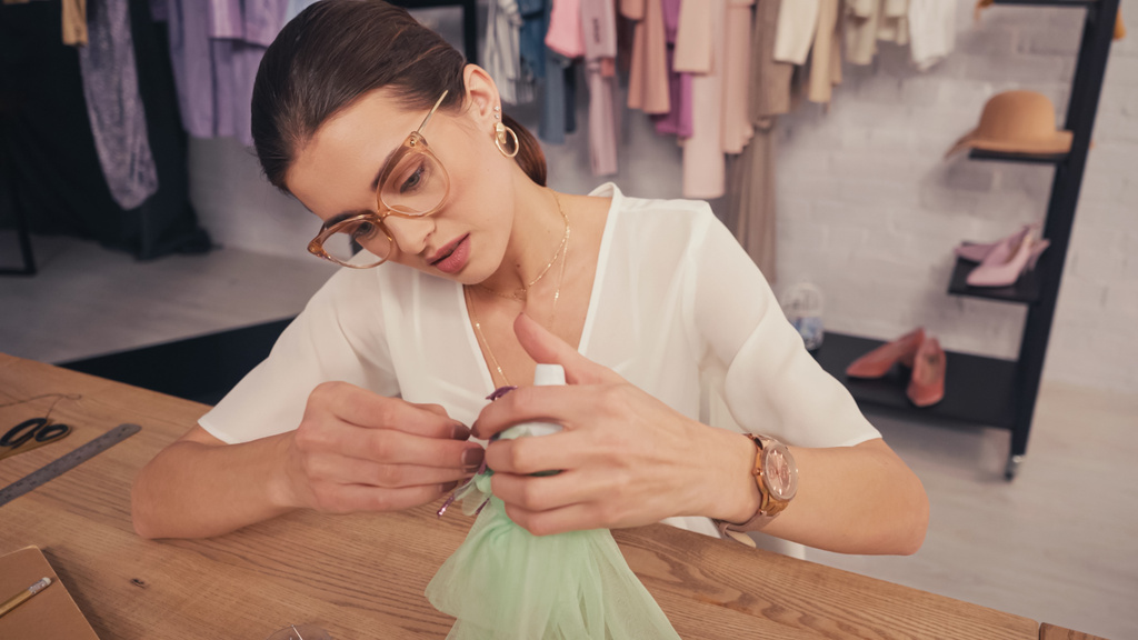 Couturière en lunettes faisant robe sur mannequin de poupée en atelier  - Photo, image
