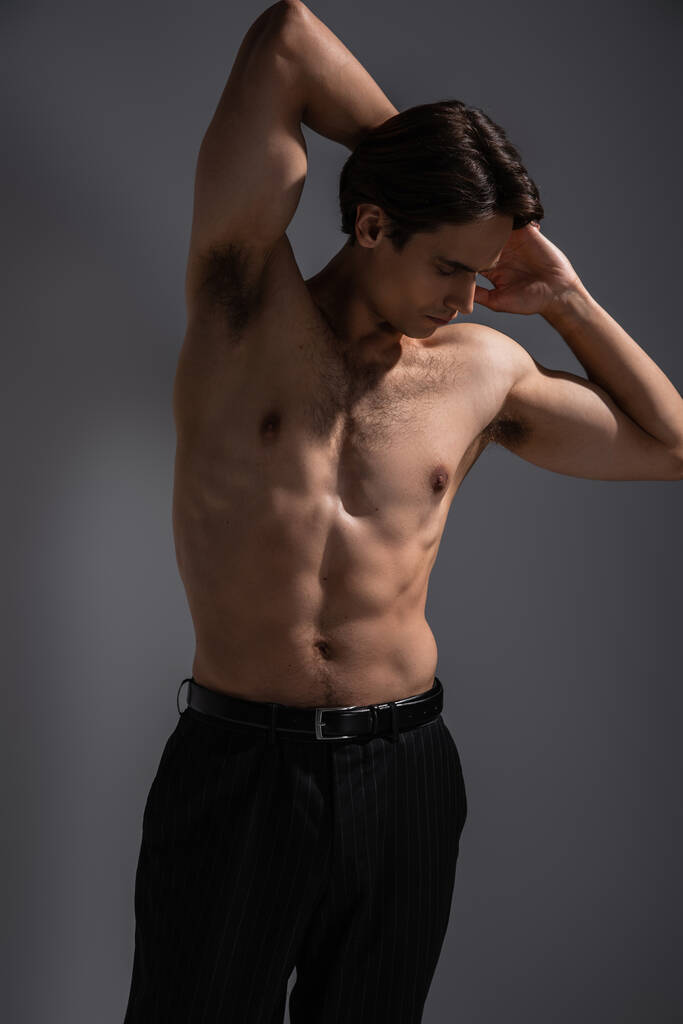 homem sexy com corpo muscular posando em calças pretas em cinza - Foto, Imagem