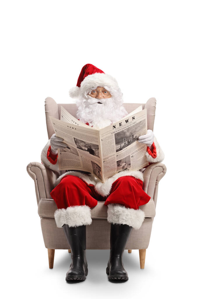 Noel Baba koltuğunda oturup beyaz arka planda izole edilmiş gazete okuyor. - Fotoğraf, Görsel