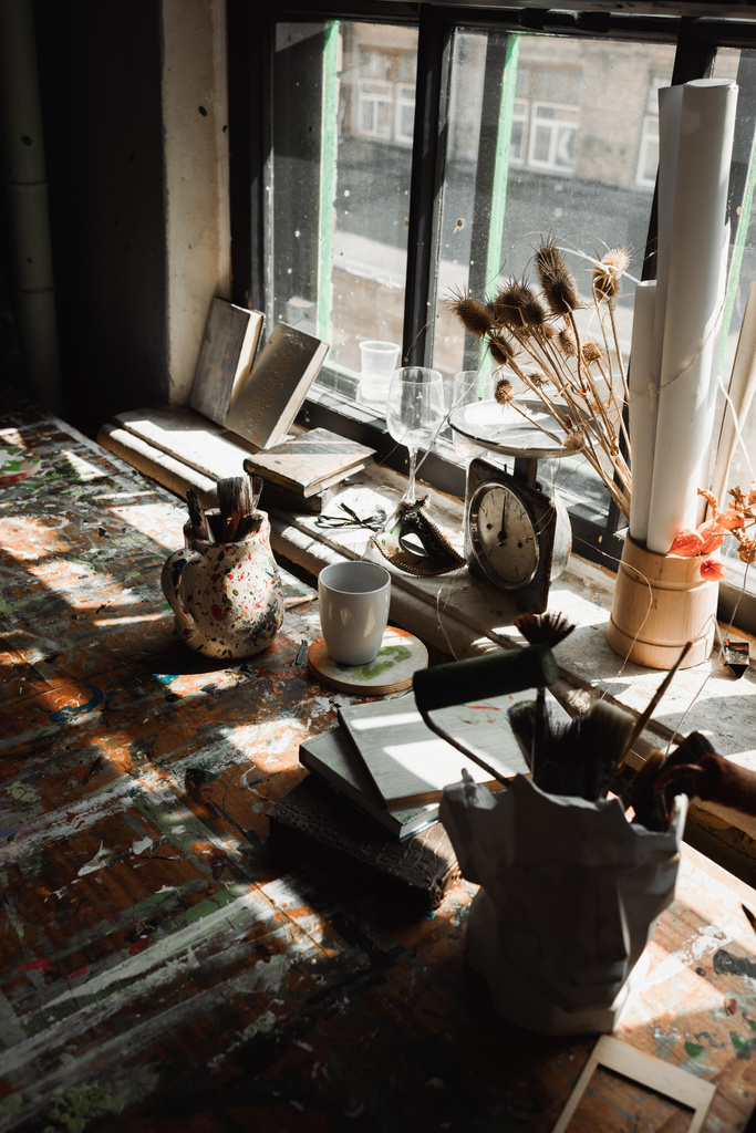 stukki maljakko ja kannu taidetta työkaluja lähellä kirjoja ja vintage asteikot karkea ikkunalaudalla maalitaulut  - Valokuva, kuva