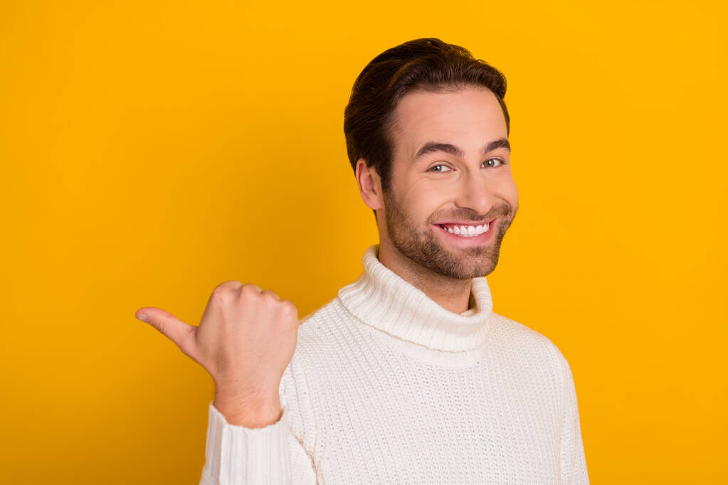 Foto van zelfverzekerde promotor guy directe vinger suggereren lege ruimte dragen witte trui geïsoleerde gele kleur achtergrond. - Foto, afbeelding