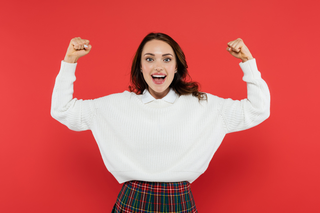 Excited woman in sweater showing yes gesture isolated on red  - Photo, Image