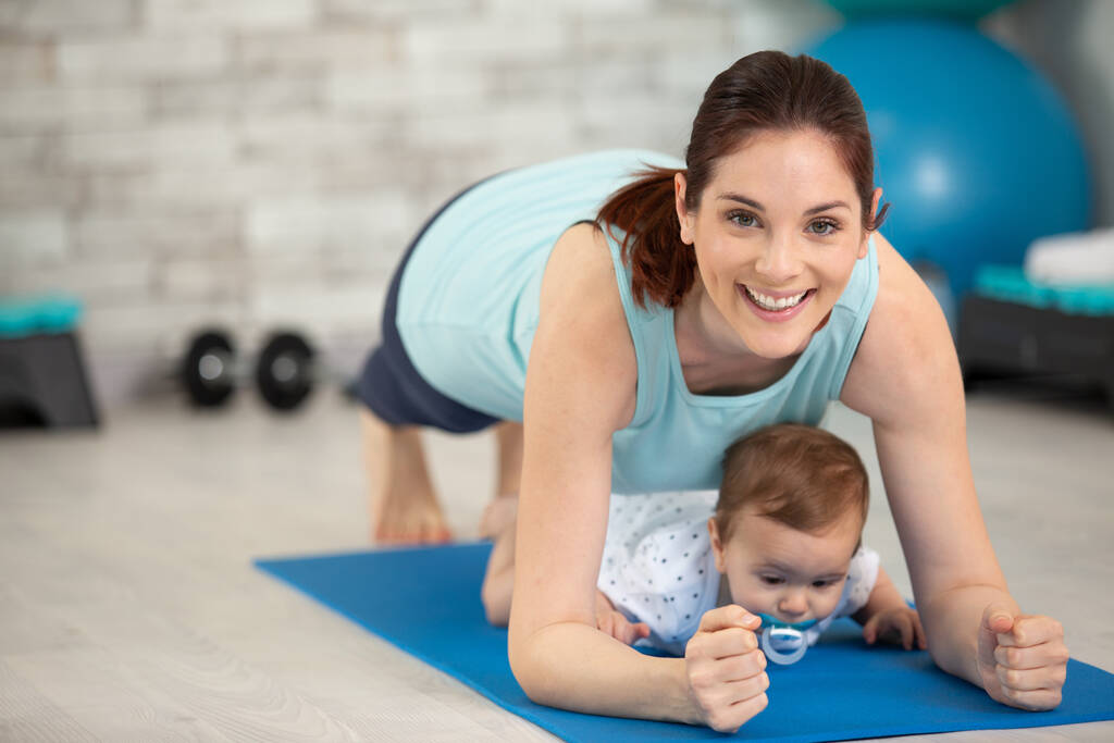 view of young mother doing plank together with her baby - Photo, Image