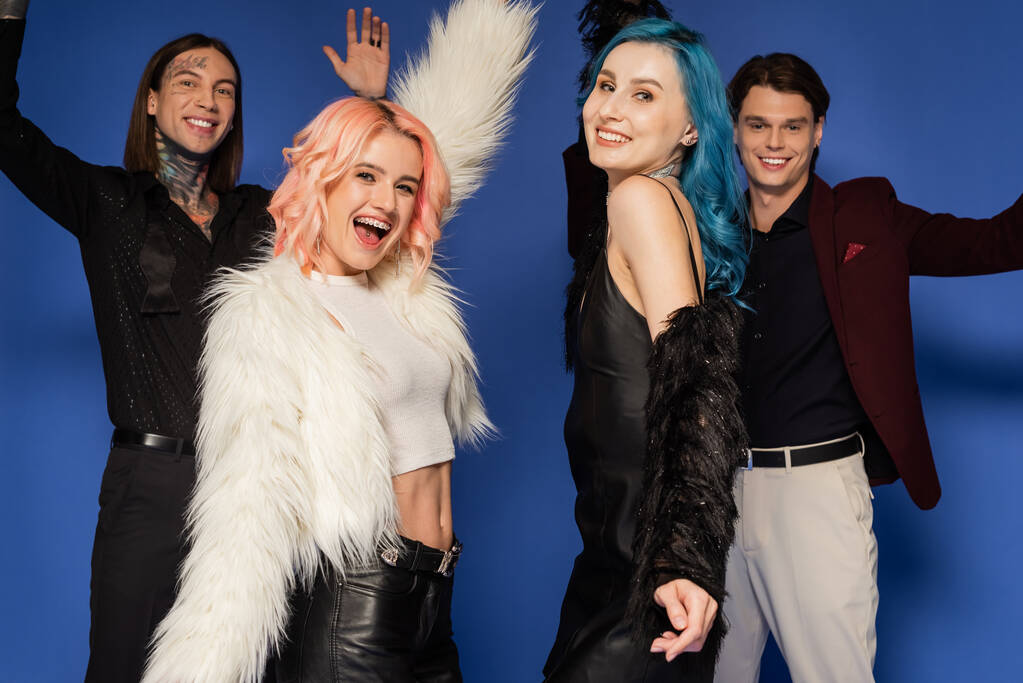 excited nonbinary person in white faux fur jacket near happy queer friends isolated on blue - Photo, Image