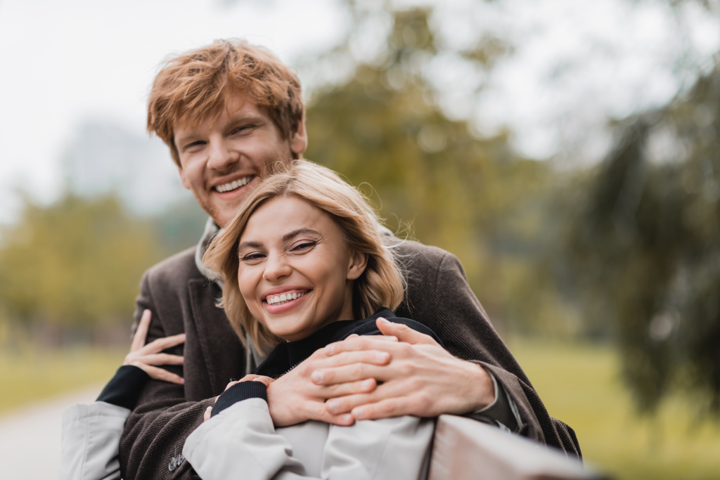 veselý mladý muž objímání pozitivní žena v zeleném parku - Fotografie, Obrázek