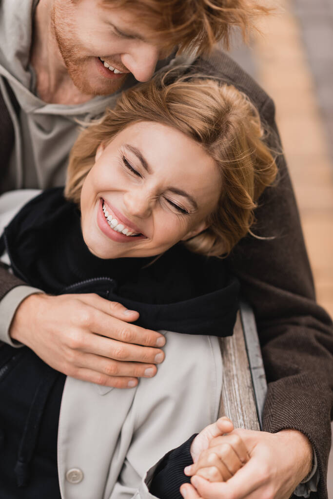hoge hoek uitzicht van vrolijke jonge man knuffelen lachende vrouw  - Foto, afbeelding
