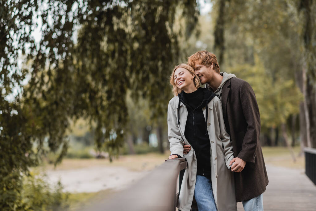 ruiva homem e mulher loira no casaco sorrindo durante a data no parque  - Foto, Imagem