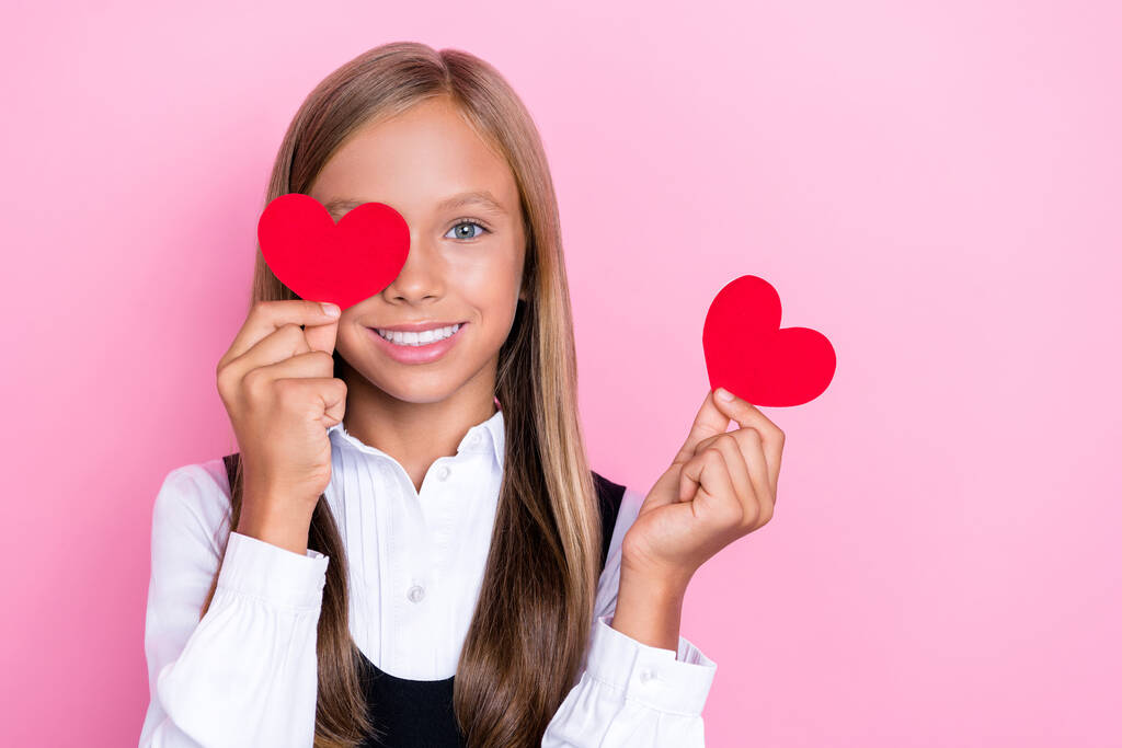 zbliżenie zdjęcie młody ładny uczennica dziewczyna pani nosić mundurek zębaty uśmiech pokrywa twarz oko czerwony papier serce izolowane na różowy kolor tło. - Zdjęcie, obraz