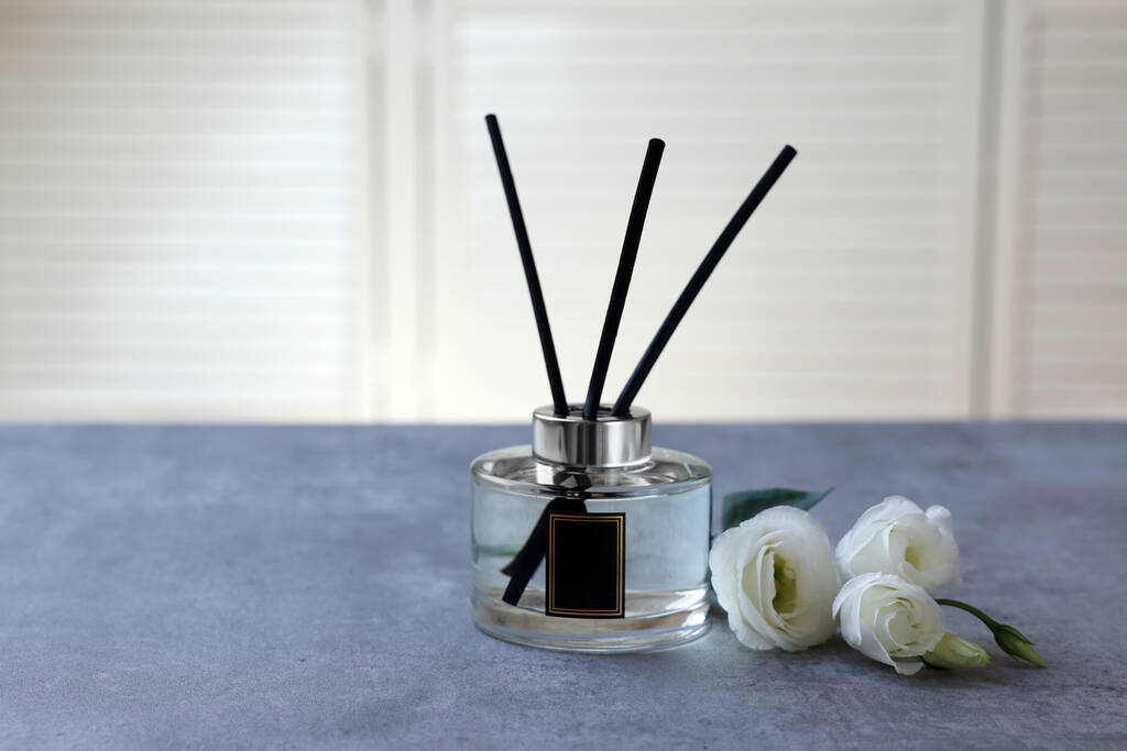 Reed diffuser and eustoma flowers on gray marble table - Foto, imagen