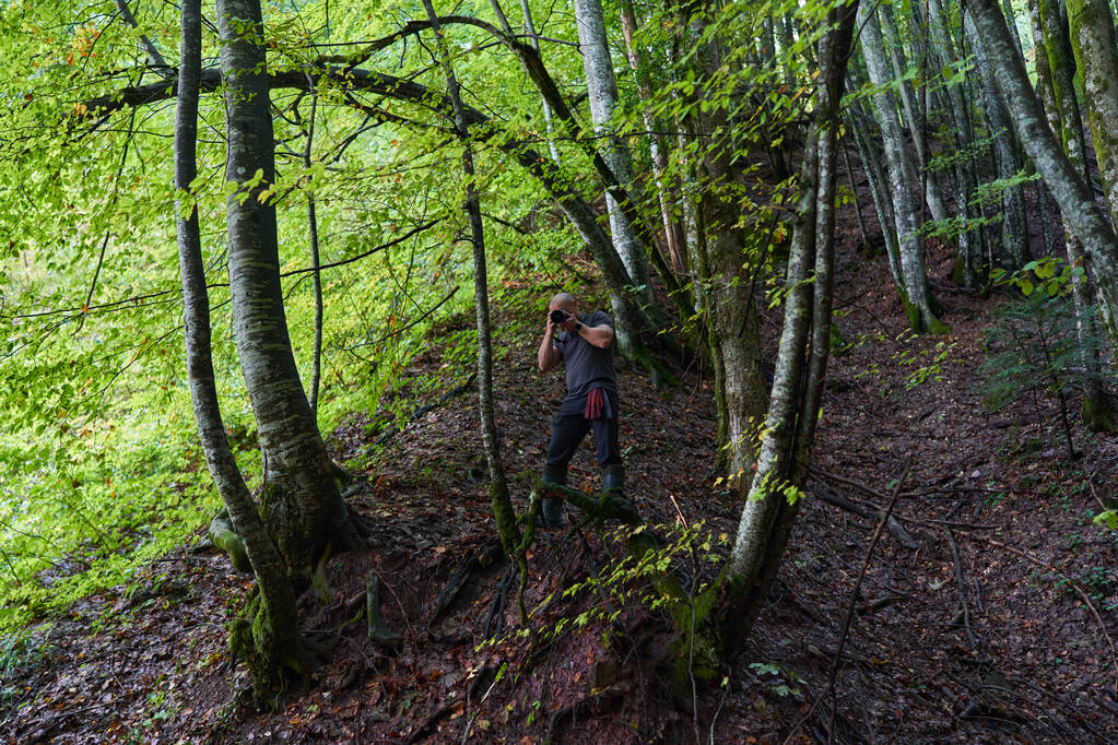 Fotógrafo profesional de la naturaleza senderismo en los bosques de montaña con cámara y mochila - Foto, Imagen