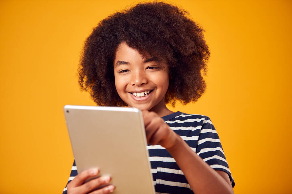 Studio Portret van jongen spelen spel op digitale tablet tegen gele achtergrond - Foto, afbeelding