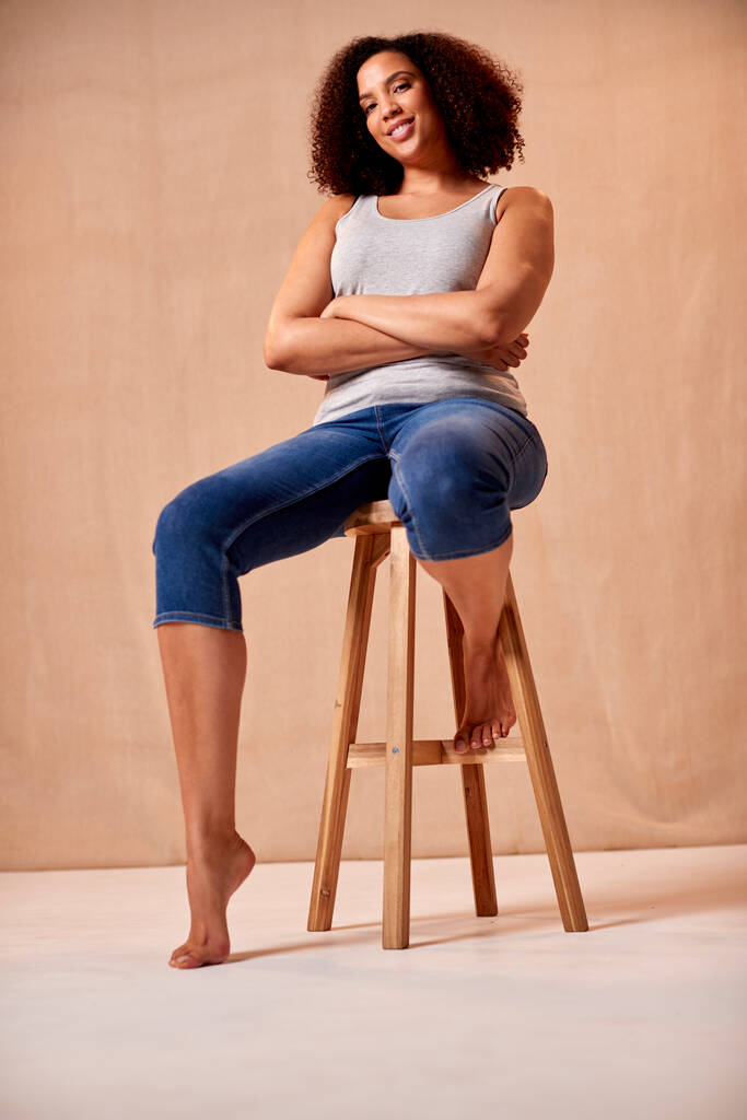 Studio Portrait Shot Of Body Positive Woman Sentado en el taburete - Foto, Imagen