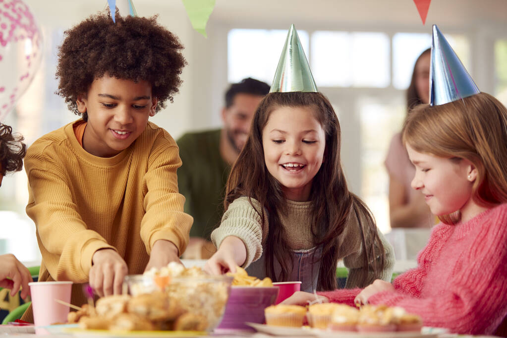 Chica con padres y amigos en casa celebrando cumpleaños comiendo bocadillos en la fiesta - Foto, imagen