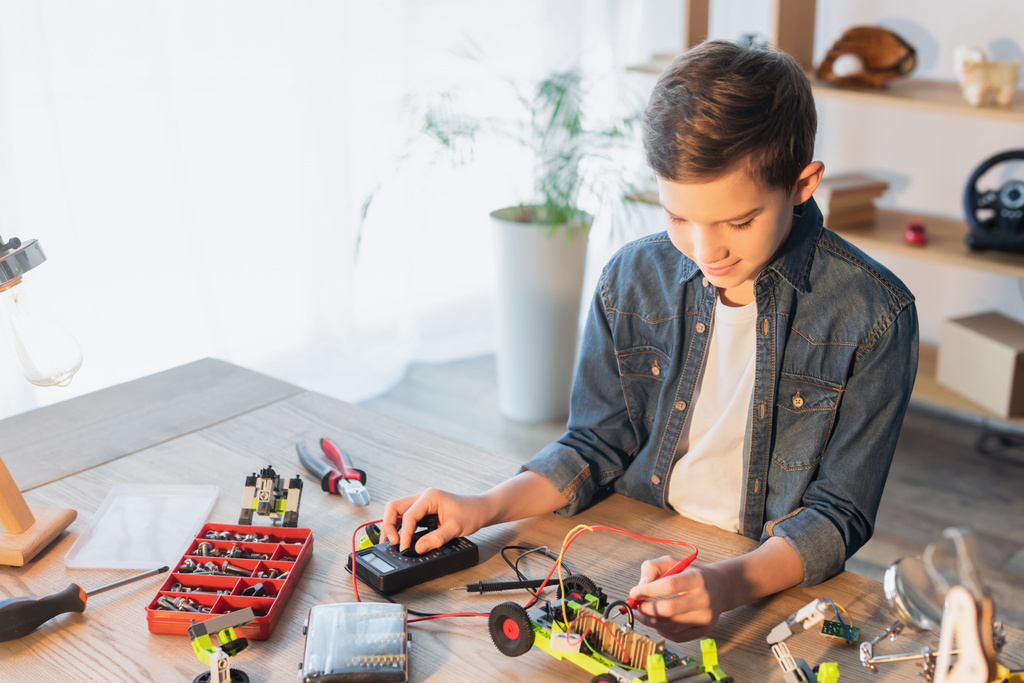 Preteen boy making robotic model with millimeter near tools and screws at home  - Foto, Bild
