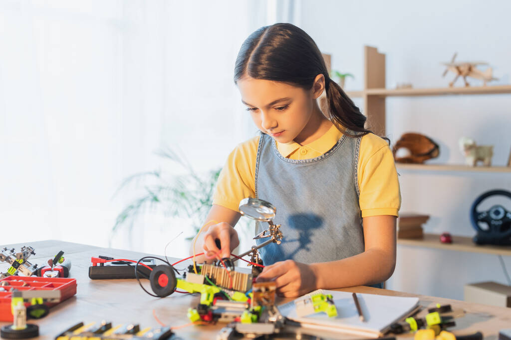 Preteen child modeling robotic model near notebook on table - Photo, Image