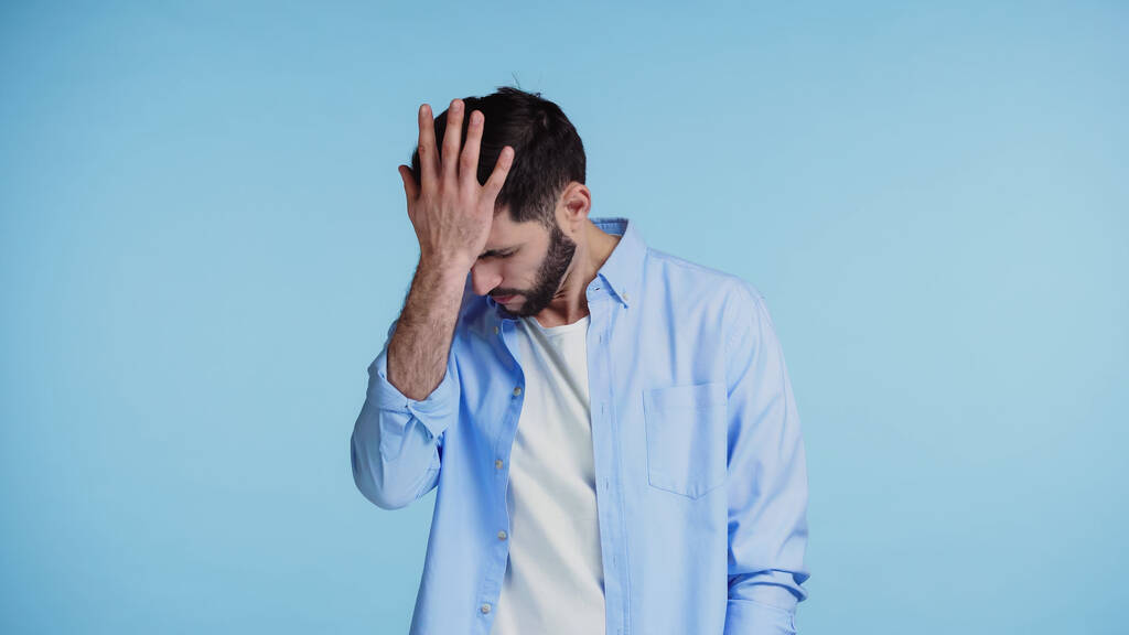 незадоволений бородатий чоловік у сорочці торкається голови з рукою ізольовано на синьому
  - Фото, зображення