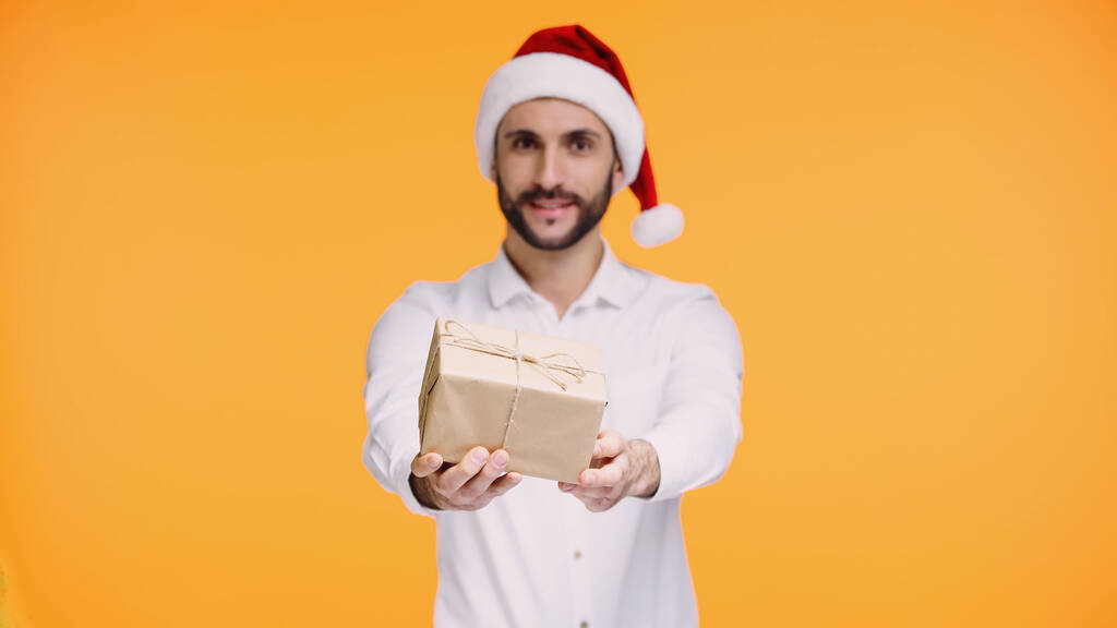 бородатий чоловік у червоному капелюсі Санта дарує різдвяний подарунок ізольовано на жовтому
  - Фото, зображення