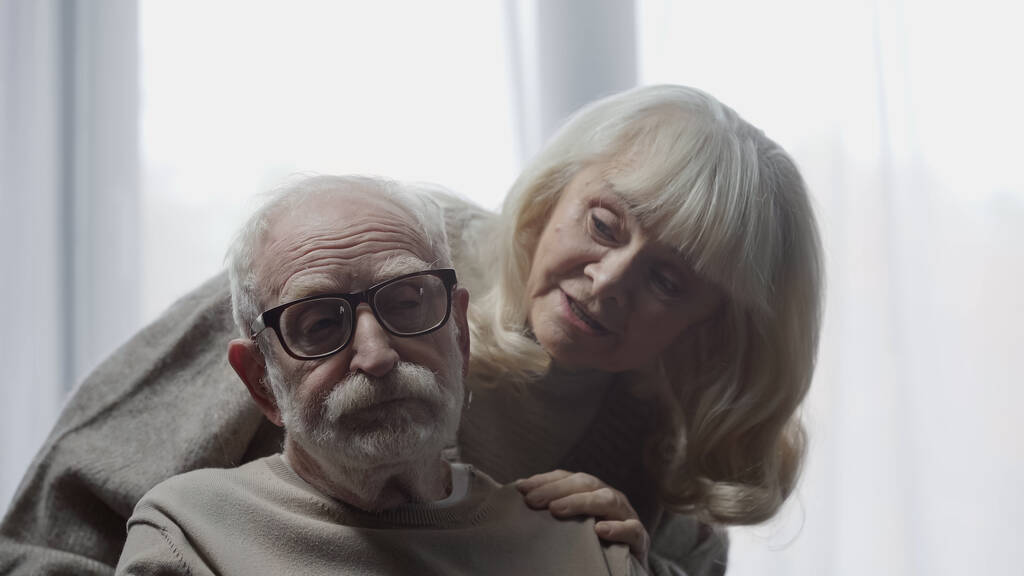 Yaşlı kadın bunamış kocasını gözlükleriyle sakinleştiriyor.  - Fotoğraf, Görsel
