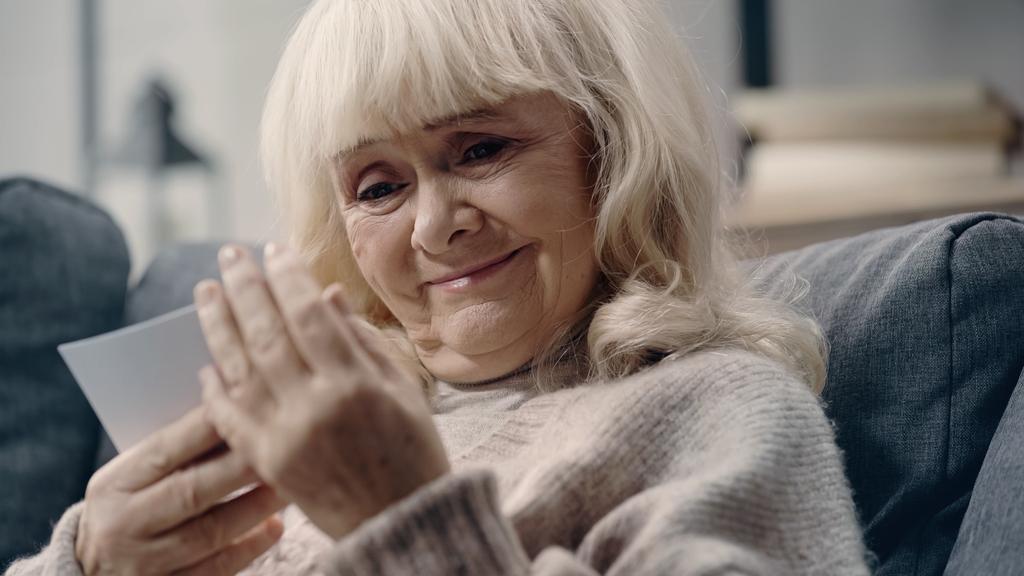 счастливая пожилая женщина со слабоумием глядя на отпечатанную фотографию  - Фото, изображение