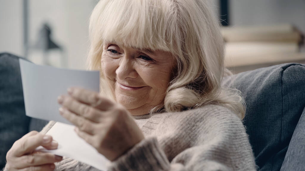 mujer mayor sonriente con demencia mirando fotografía impresa  - Foto, Imagen