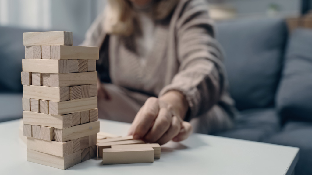bijgesneden weergave van senior vrouw met dementie spelen in blokken hout spel - Foto, afbeelding