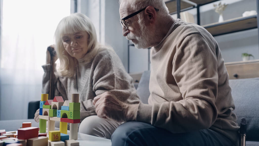 認知症の引退した夫婦はテーブルの上にカラフルなビルディングブロックで遊んでいます  - 写真・画像