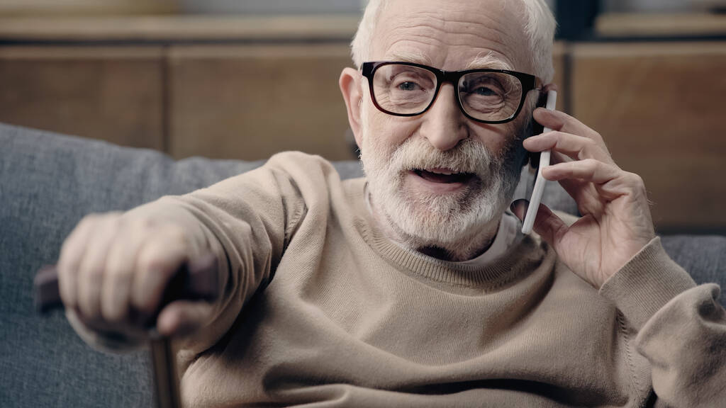 brodaty seniorek w okularach rozmawiający na smartfonie w domu  - Zdjęcie, obraz
