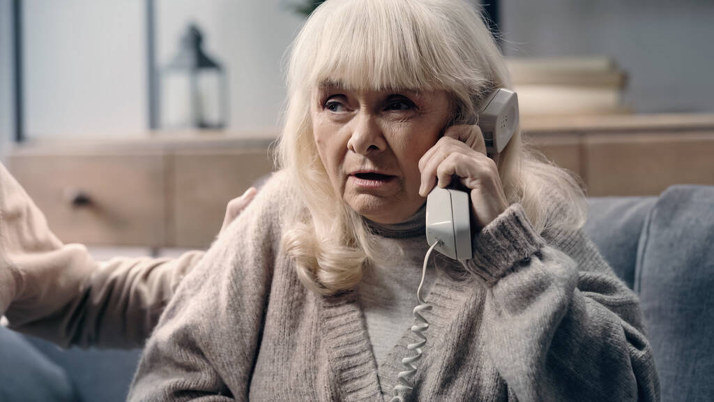 сомнительная пожилая женщина со слабоумием разговаривает по телефону рядом с мужем  - Фото, изображение