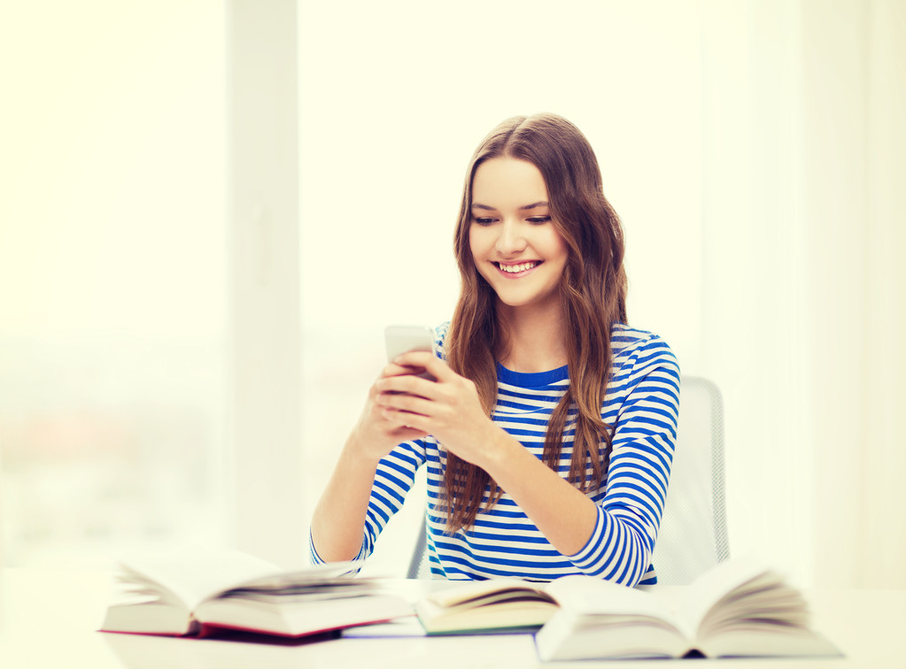 Hymyilevä opiskelija tyttö älypuhelimen ja kirjoja
 - Valokuva, kuva