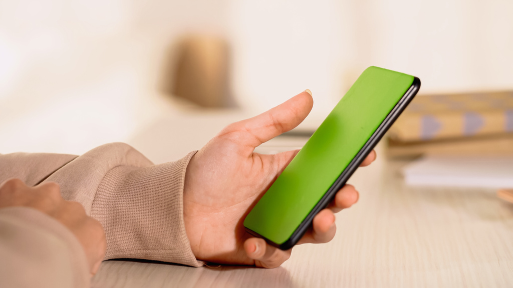Vista parziale della donna che tiene il cellulare con schermo verde a casa  - Foto, immagini