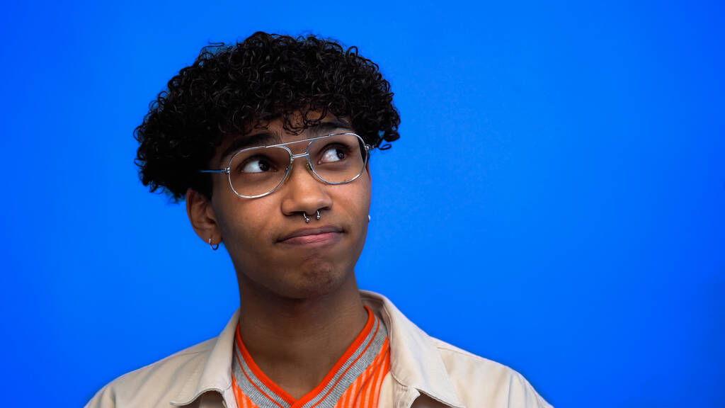 Pensif jeune homme afro-américain à lunettes regardant loin isolé sur bleu  - Photo, image