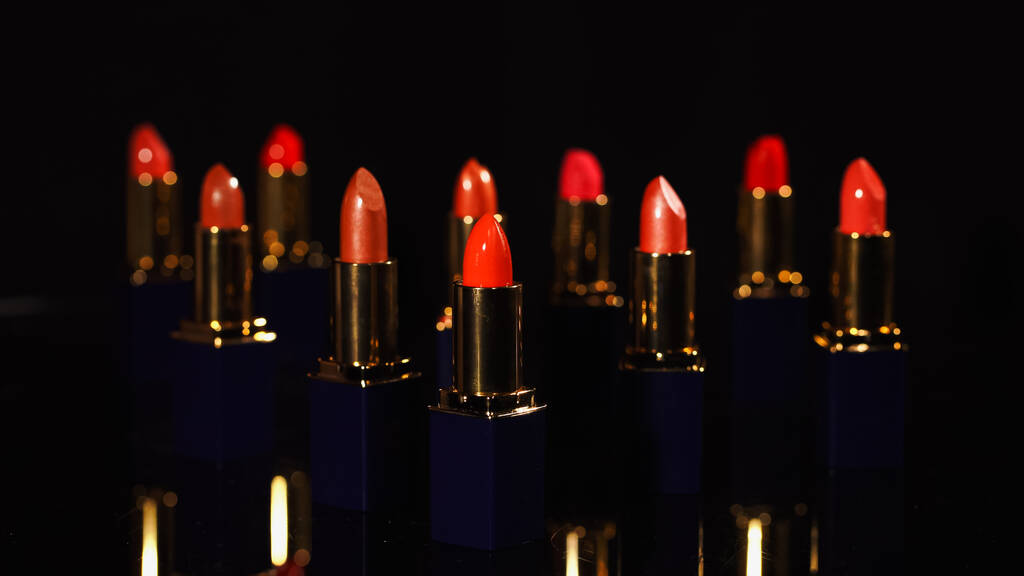 Vista de cerca de lápices labiales de color rojo brillante sobre fondo negro  - Foto, imagen