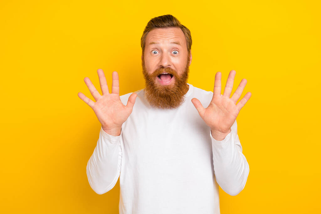 Portrait photo of young funny face reaction red hair beard man hands up scary you isolated on yellow color background. - Photo, Image