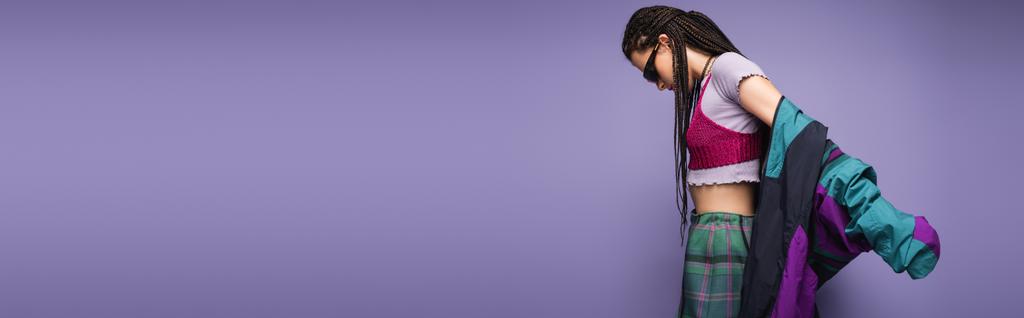 side view of woman in sunglasses and vintage style clothes posing isolated on purple, banner - Photo, Image