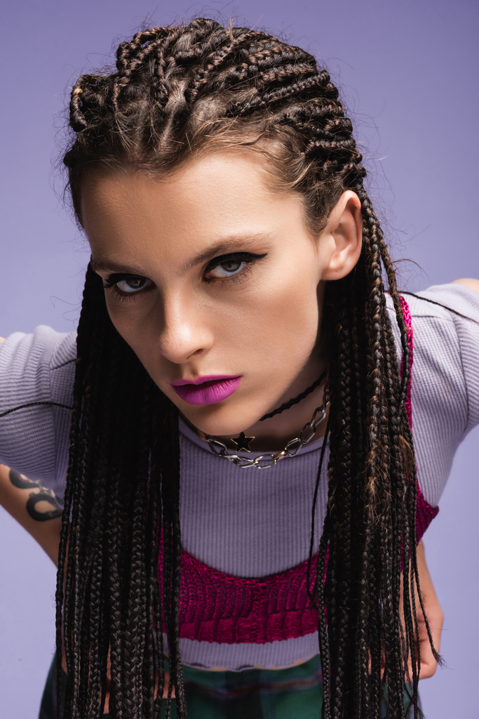portrait of trendy woman with dreadlocks and makeup looking at camera isolated on purple - Photo, Image