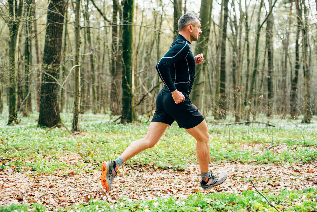 широкий знімок спортивного чоловіка, що бігає в прекрасному весняному лісі. Спортивно оздоровча концепція
 - Фото, зображення