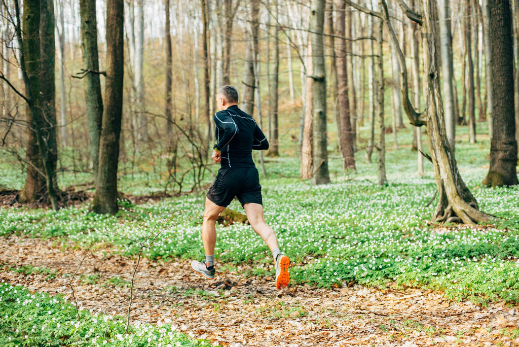 tiro largo de homem desportivo correndo na bela floresta de primavera. Conceito de desporto e bem-estar - Foto, Imagem